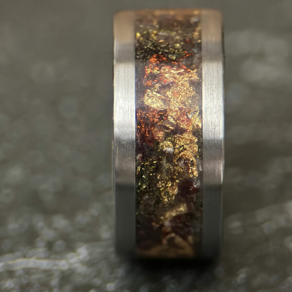 A ring with stainless steel sides and variety of gold, red, green, and other leafs.