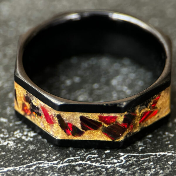 Octagon black ceramic ring with golden dust and red opal inlay.