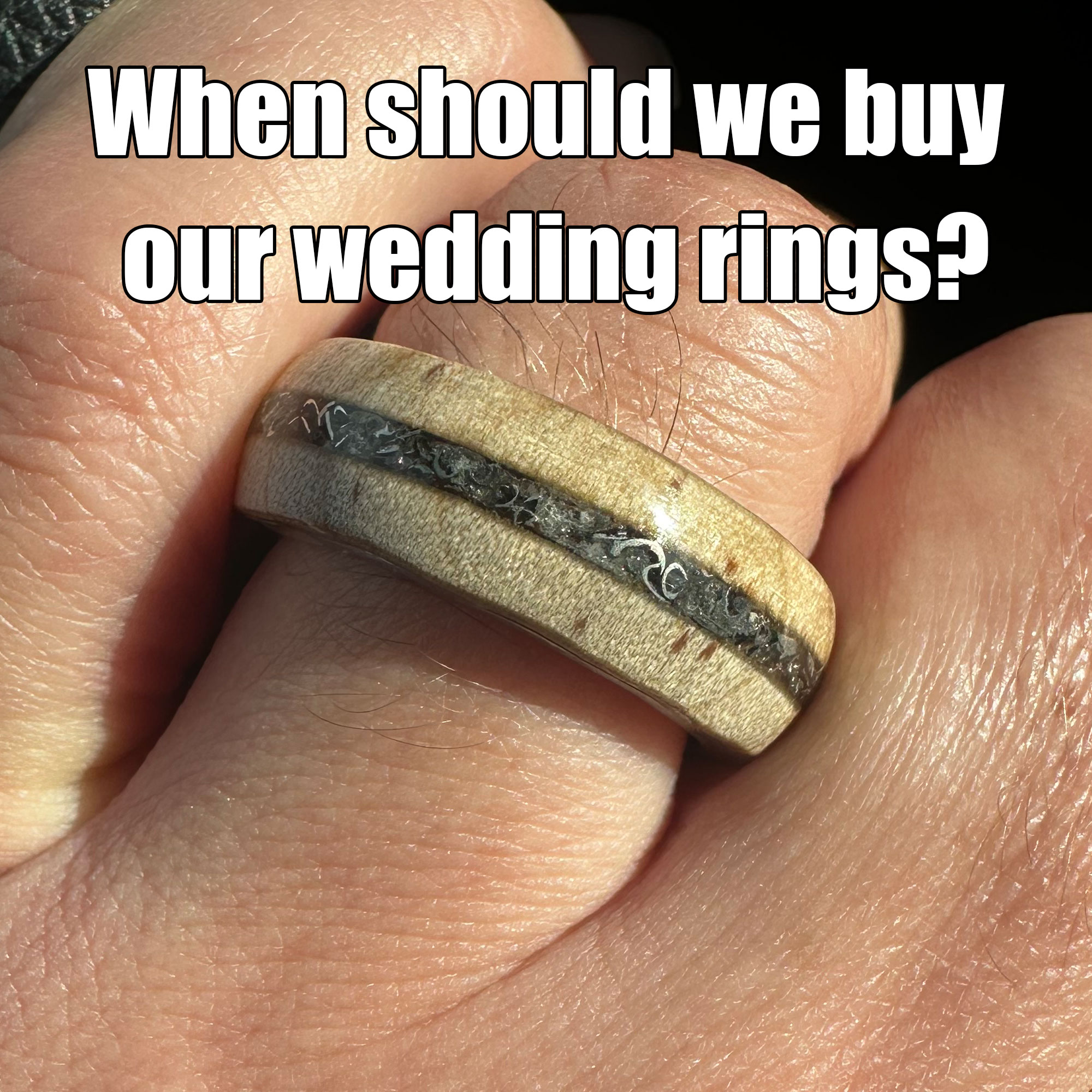 Picture of wood and Sherman tank ring worn on hand with "when should we buy our wedding rings" written on it. For post, when to buy wedding rings.