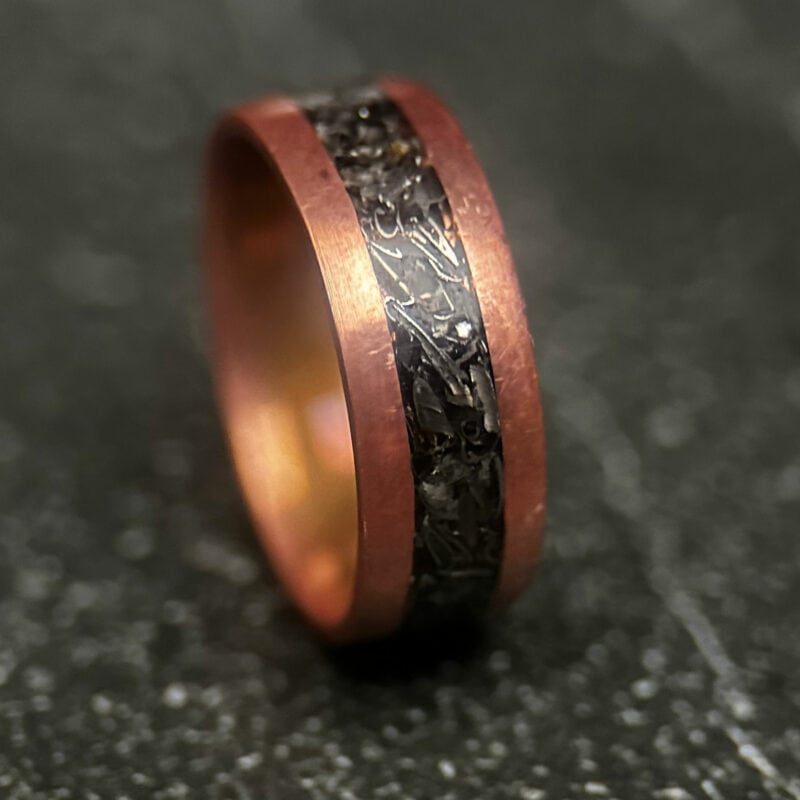 Copper ring with tank scrap on a dark surface