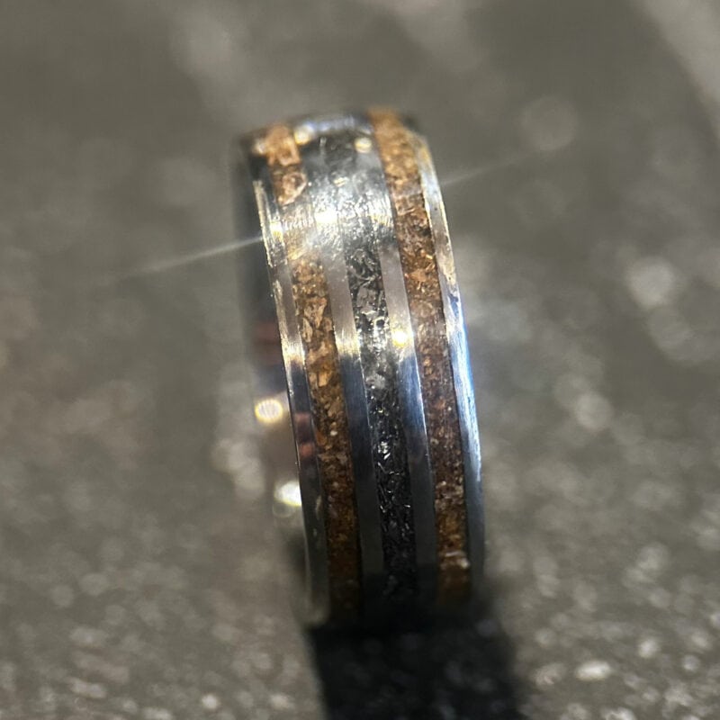 Triceratops fossil ring with meteorite in center on dark background