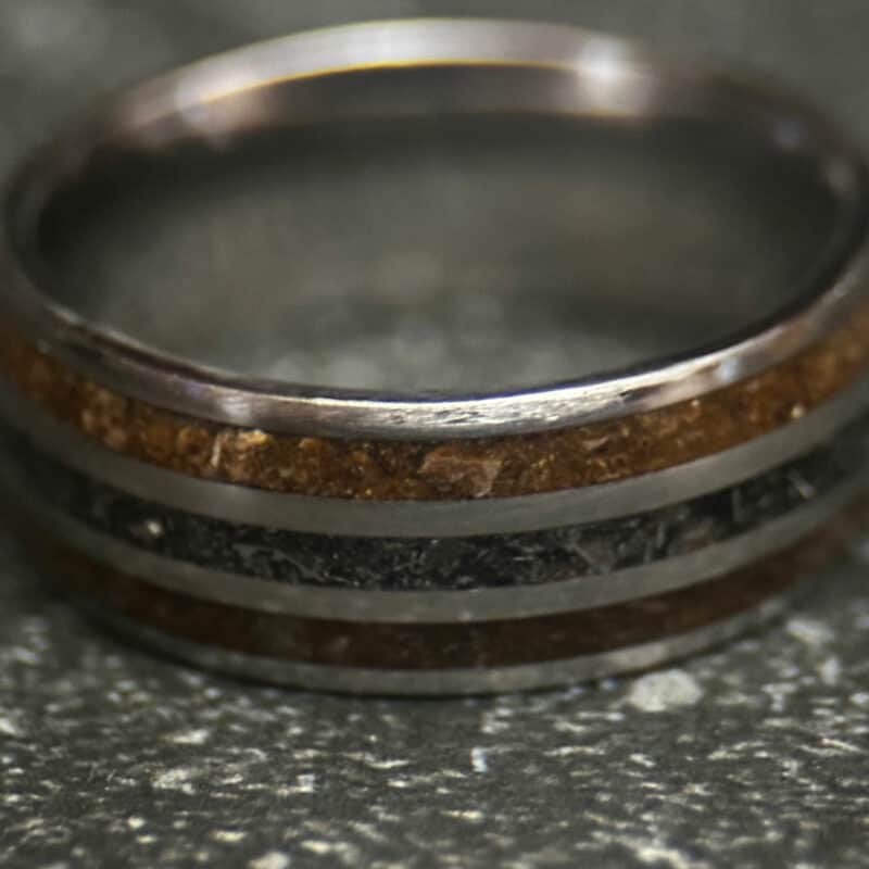 Triceratops fossil ring with meteorite in center on dark background