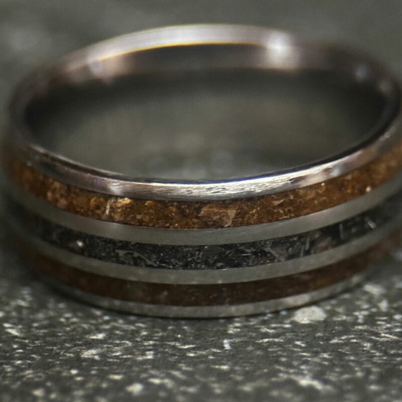 Triceratops fossil ring with meteorite in center on dark background