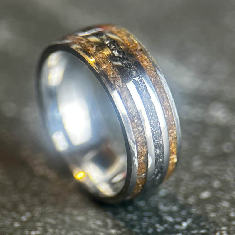 Triceratops fossil ring with meteorite in center on dark background