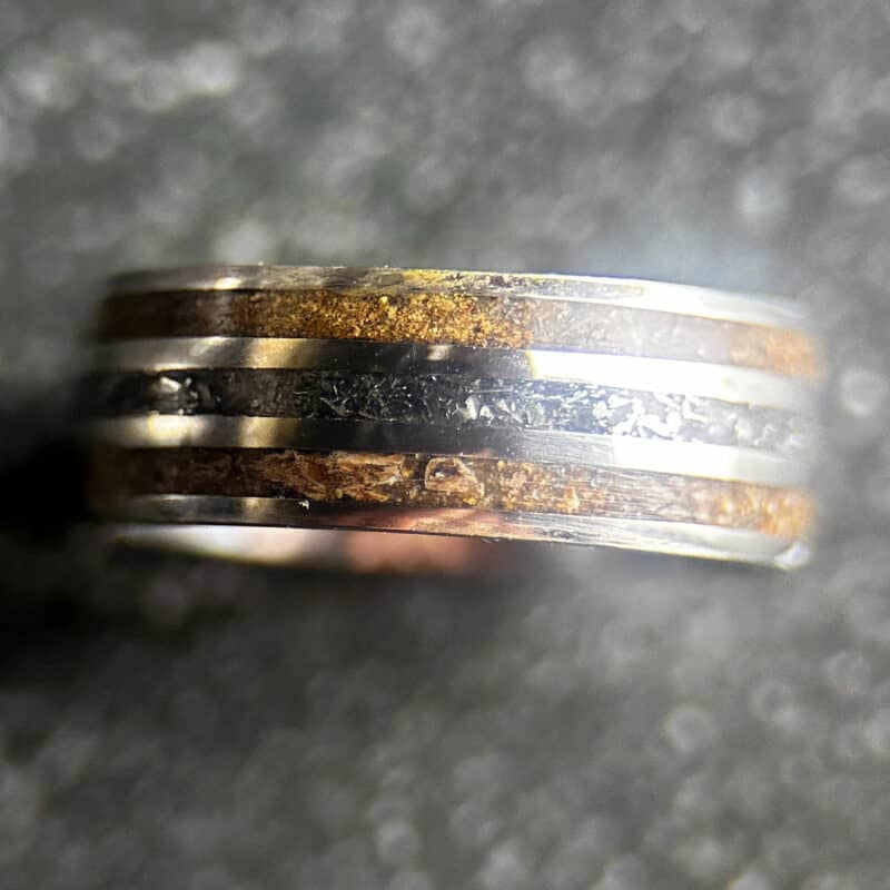 Triceratops fossil ring with meteorite in center on dark background