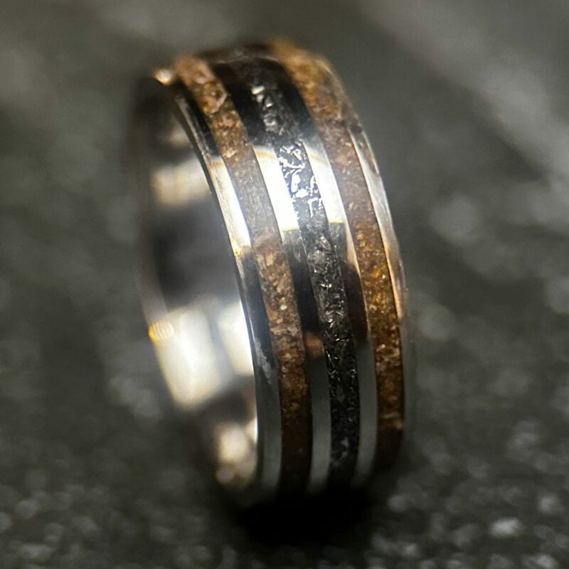 Triceratops fossil ring with meteorite in center on dark background