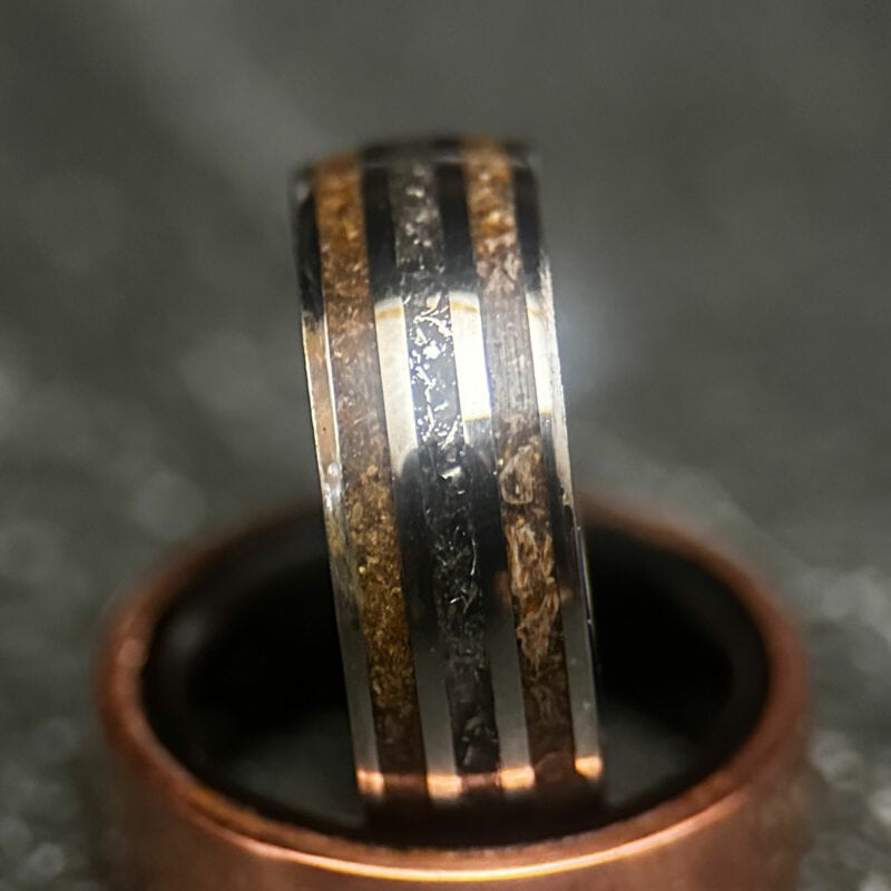 Triceratops fossil ring with meteorite in center on dark background
