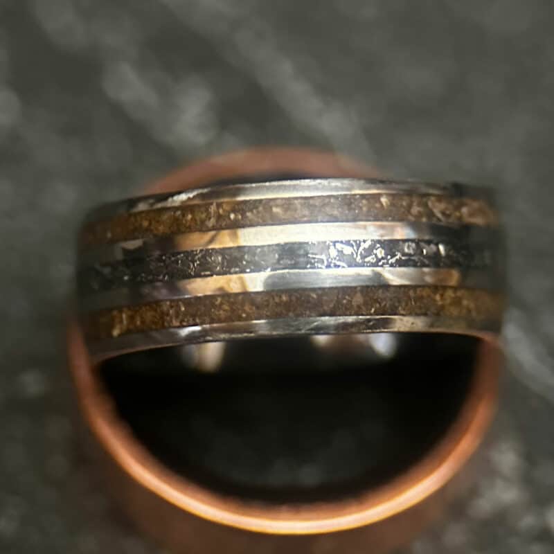Triceratops fossil ring with meteorite in center on dark background