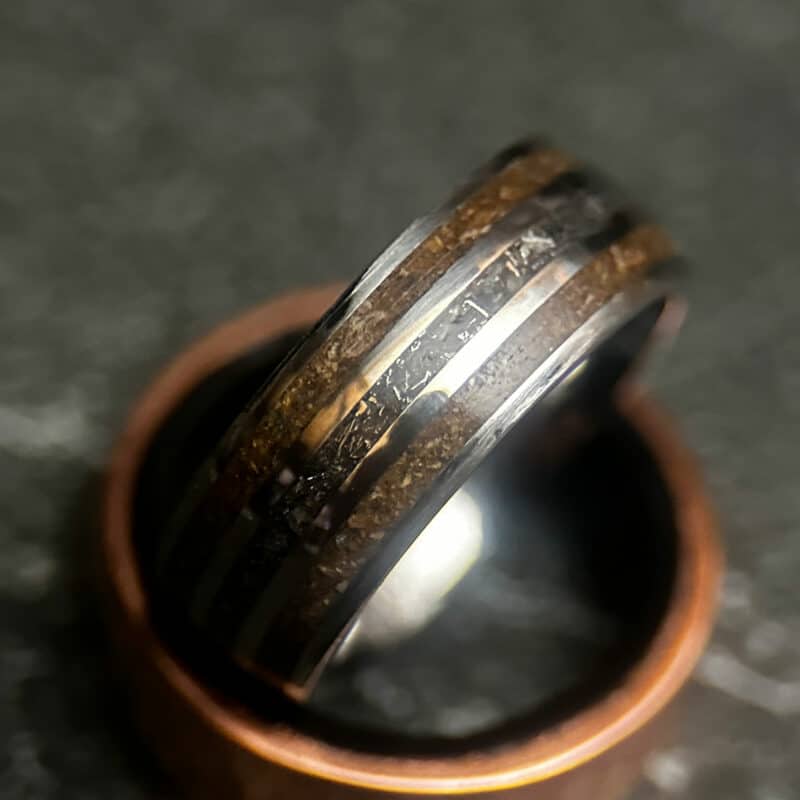 Triceratops fossil ring with meteorite in center on dark background