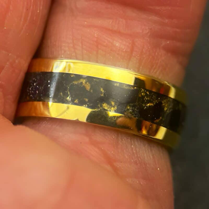 Nordic gold ring with blue gold stone inlay on a finger.