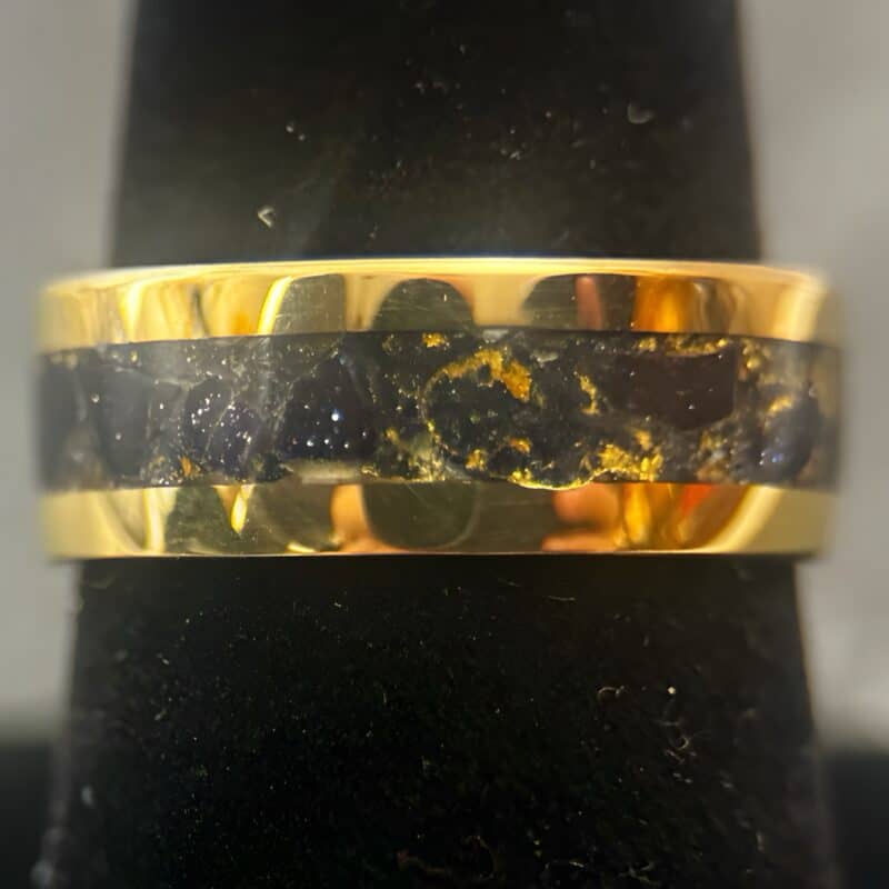 Nordic gold ring with blue gold stone inlay on a black stand.