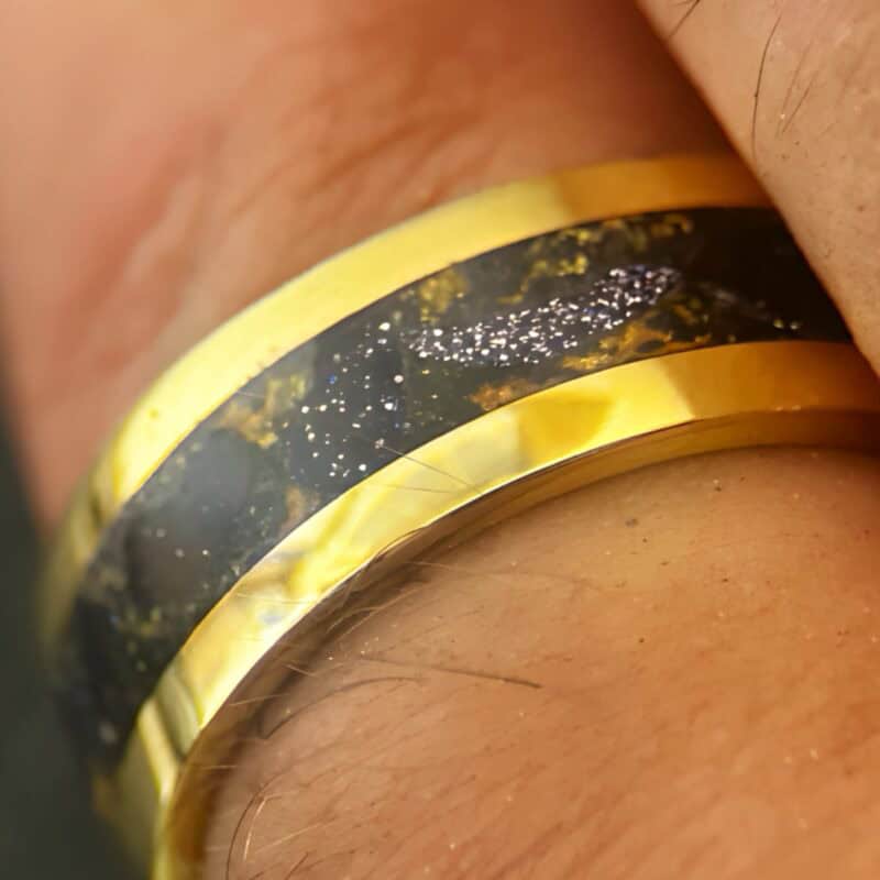 Nordic gold ring with blue gold stone inlay on a finger.