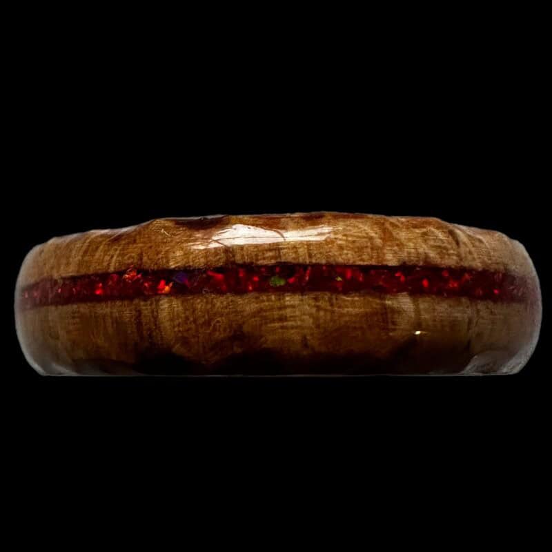 Ambrosia maple ring with red opal inlay, burnt edges, and stainless steel core. Set on black background.