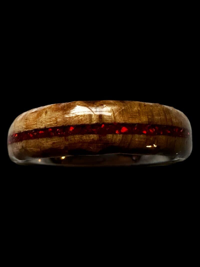 Ambrosia maple ring with red opal inlay, burnt edges, and stainless steel core. Set on black background.