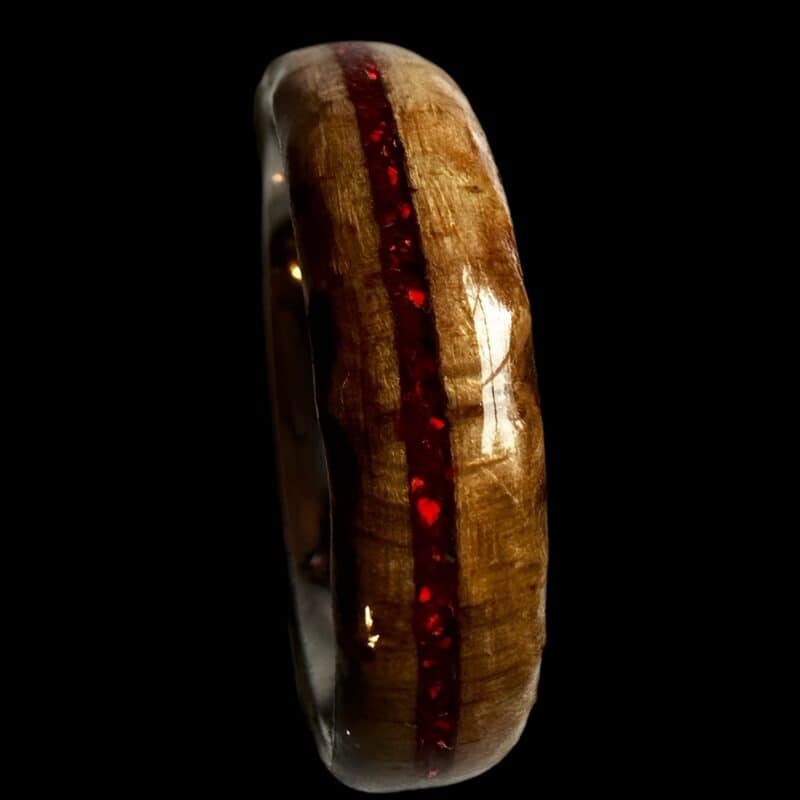 Ambrosia maple ring with red opal inlay, burnt edges, and stainless steel core. Set on black background.