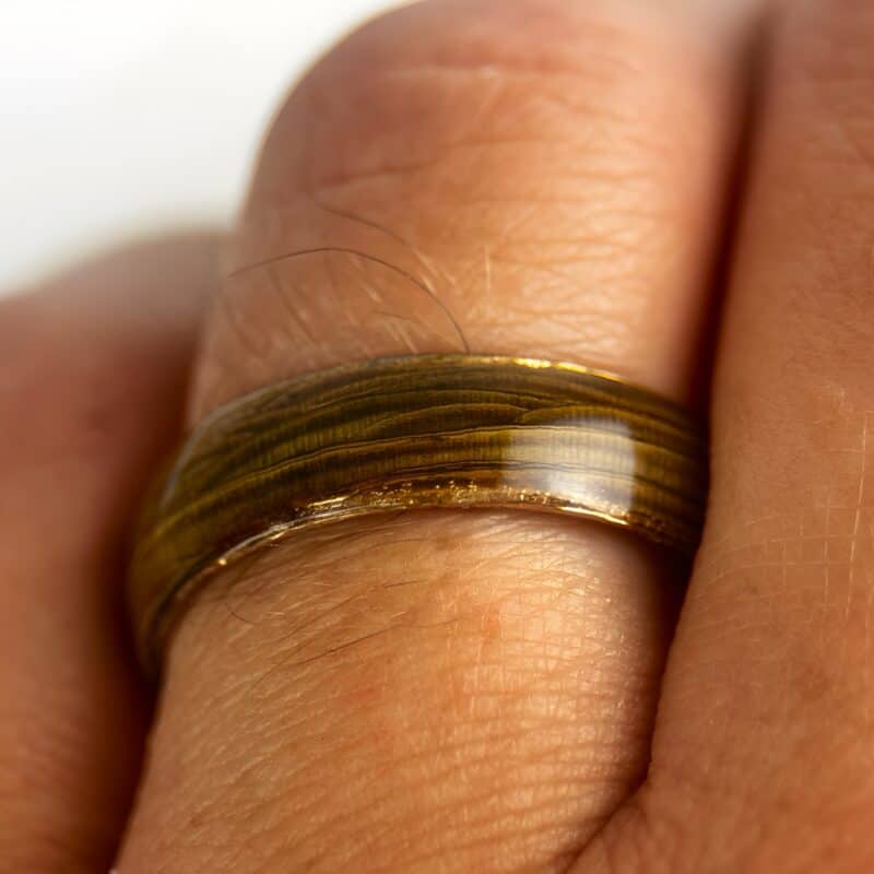 Driftwood ring with copper comfort core on finger.