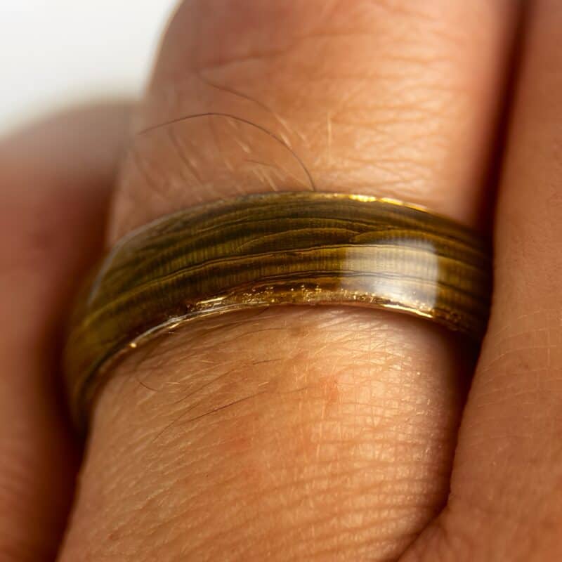 Driftwood ring with copper core on finger.