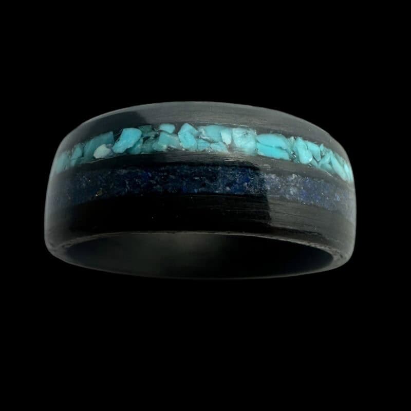 Pregnancy and infant loss birthstone ring shown with blue powder and turquoise. Set in black carbon fiber ring.