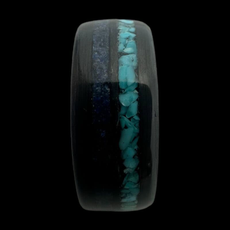 Pregnancy and infant loss birthstone ring shown with blue powder and turquoise. Set in black carbon fiber ring.