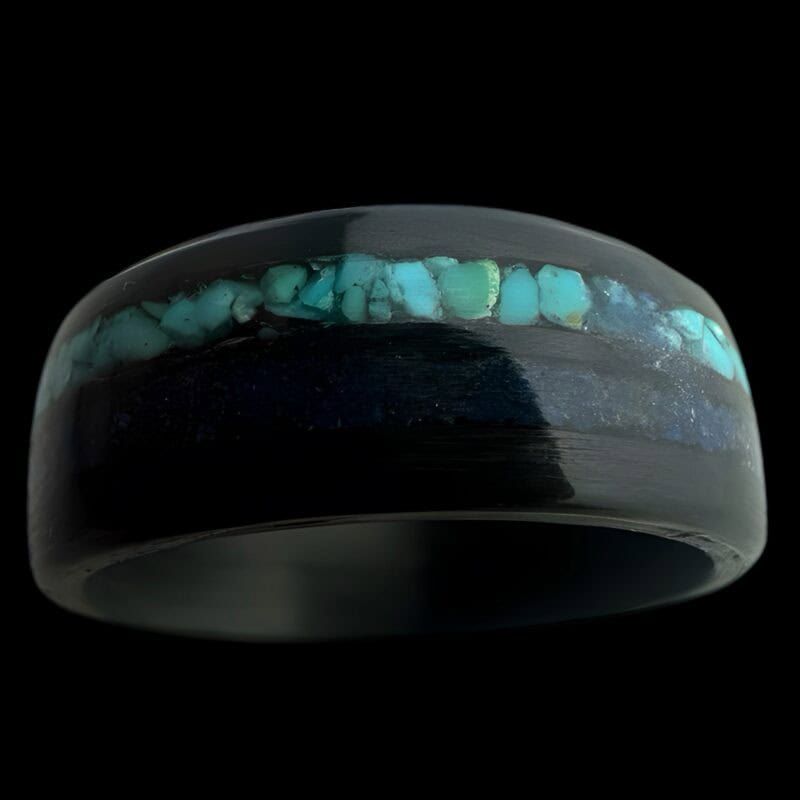 Pregnancy and infant loss birthstone ring shown with blue powder and turquoise. Set in black carbon fiber ring.
