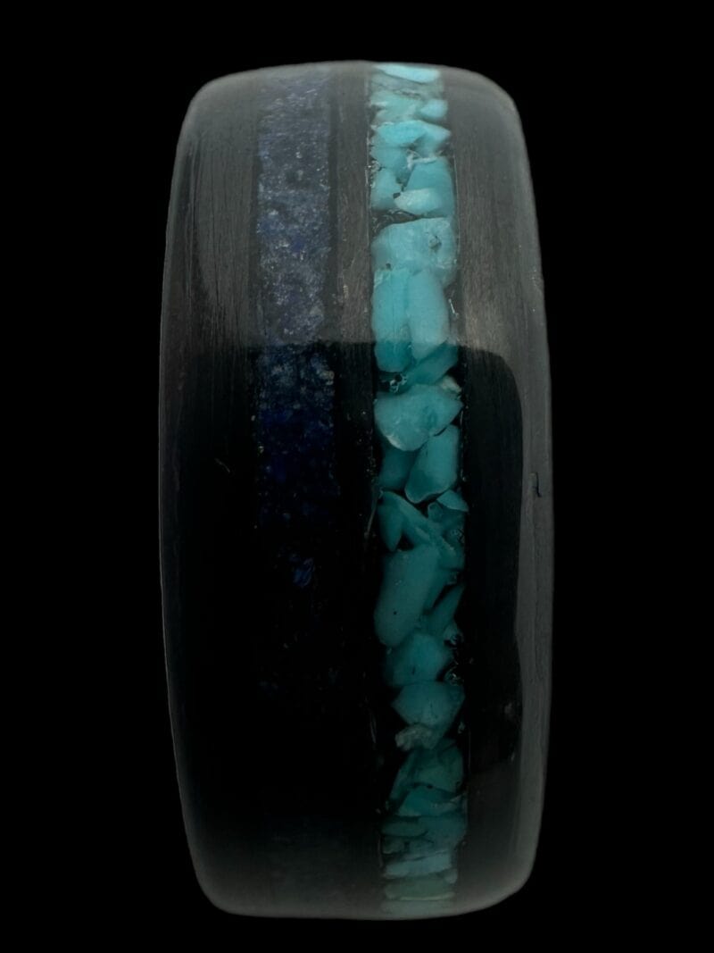 Pregnancy and infant loss birthstone ring shown with blue powder and turquoise. Set in black carbon fiber ring.