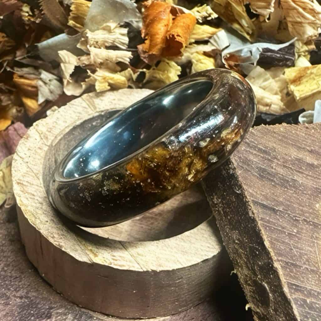 Wood composite ring set in a wood dust background. One of the best mens wedding rings you can find.